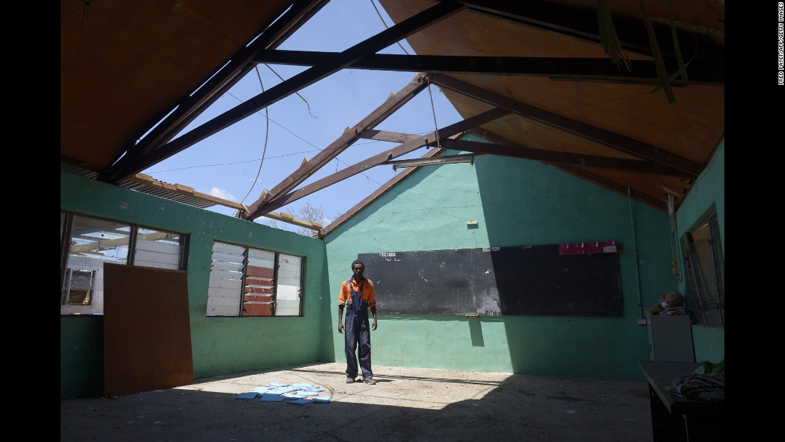 A man stands under the damaged rooftop of a school in Vanuatu&#39;s capital, Port Vila, on March 18.