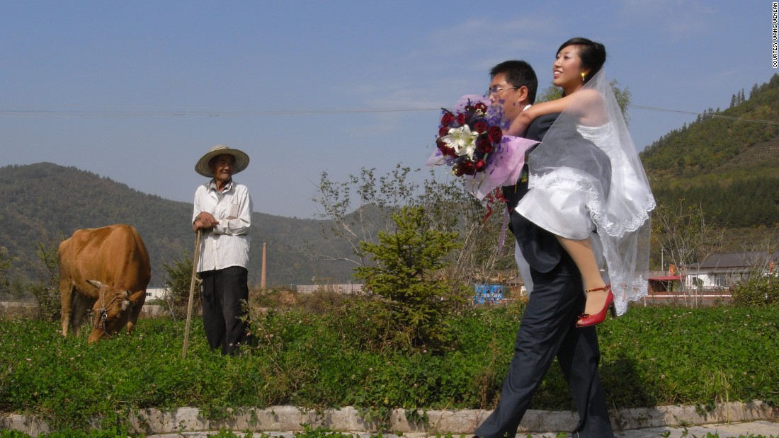 A groom carries his bride through a field in Baishan, Jilin province in 2007 as an old man looks on. Wang&#39;s work often reveals the clashes between tradition and modernity in China.