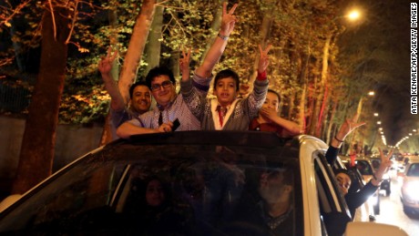 People stand in the sunroof of a car and flash the &#39;V for Victory&#39; sign as they celebrate on Valiasr street in northern Tehran on April 2, 2015, after the announcement of an agreement on Iran nuclear talks. Iran and global powers sealed a deal on April 2 on plans to curb Tehran&#39;s chances for getting a nuclear bomb, laying the ground for a new relationship between the Islamic republic and the West.