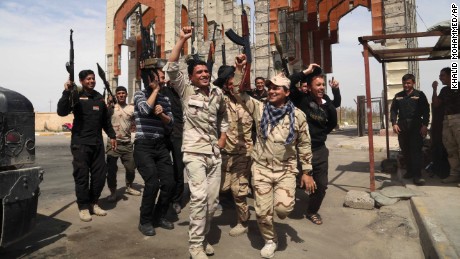 Iraqi security forces chant slogans against ISIS in Tikrit, Iraq, after reopening the main gate of their base, that was closed for months while ISIS occupied the town. 