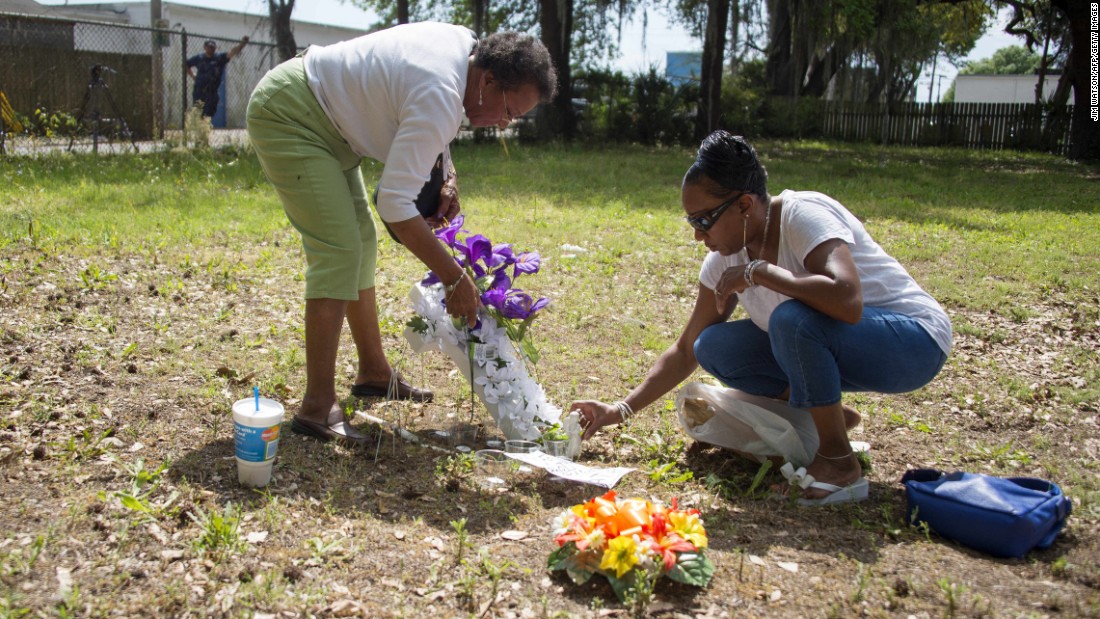 Scott&#39;s cousin Barbara, right, and her mother, Evaliana Smalls, lay flowers at the lot where the shooting took place.