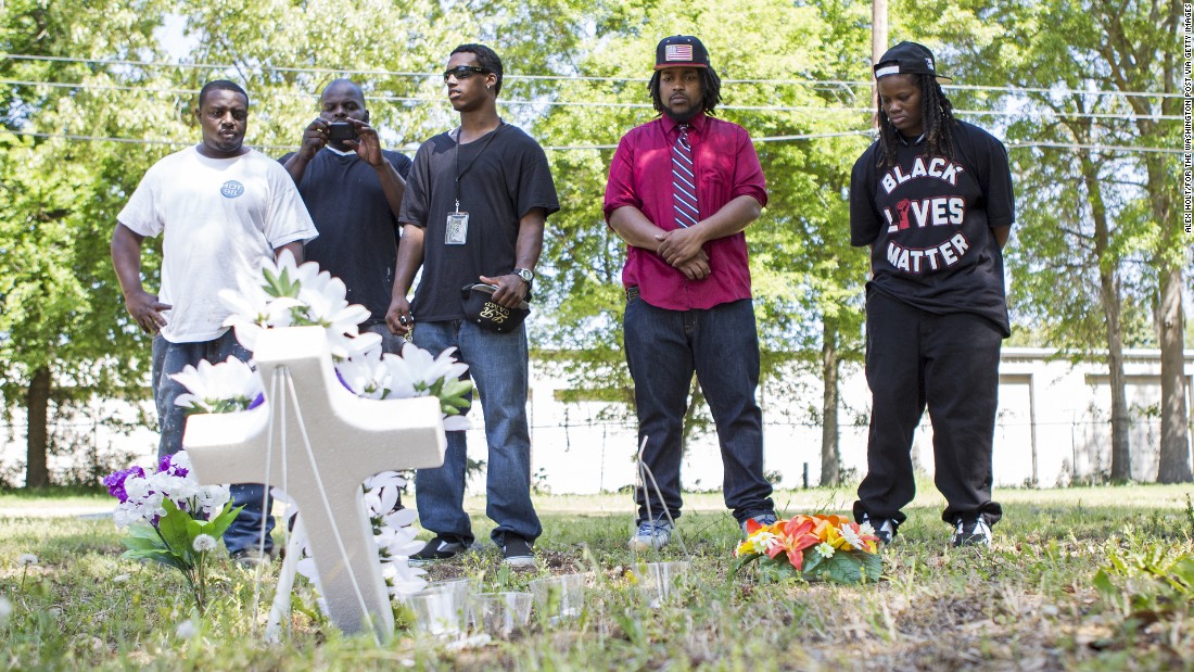 Darrell Mikell, Aaron Moses, Justin Lewis and Quin Dalton stand April 8 near the site where Scott was shot and killed. The person in the background is unidentified.