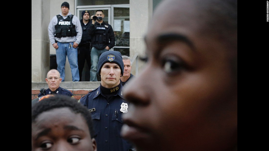 A police officer films protesters from the steps of the Western District station on April 23.