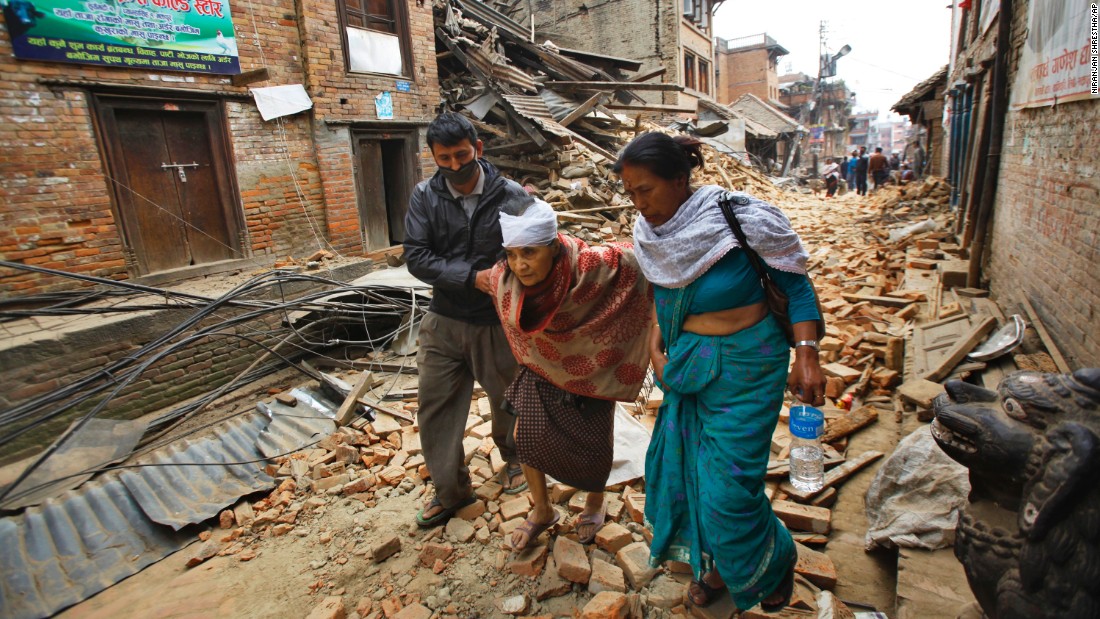 An elderly woman is helped to her home after being treated for her injuries in Bhaktapur on April 26. 