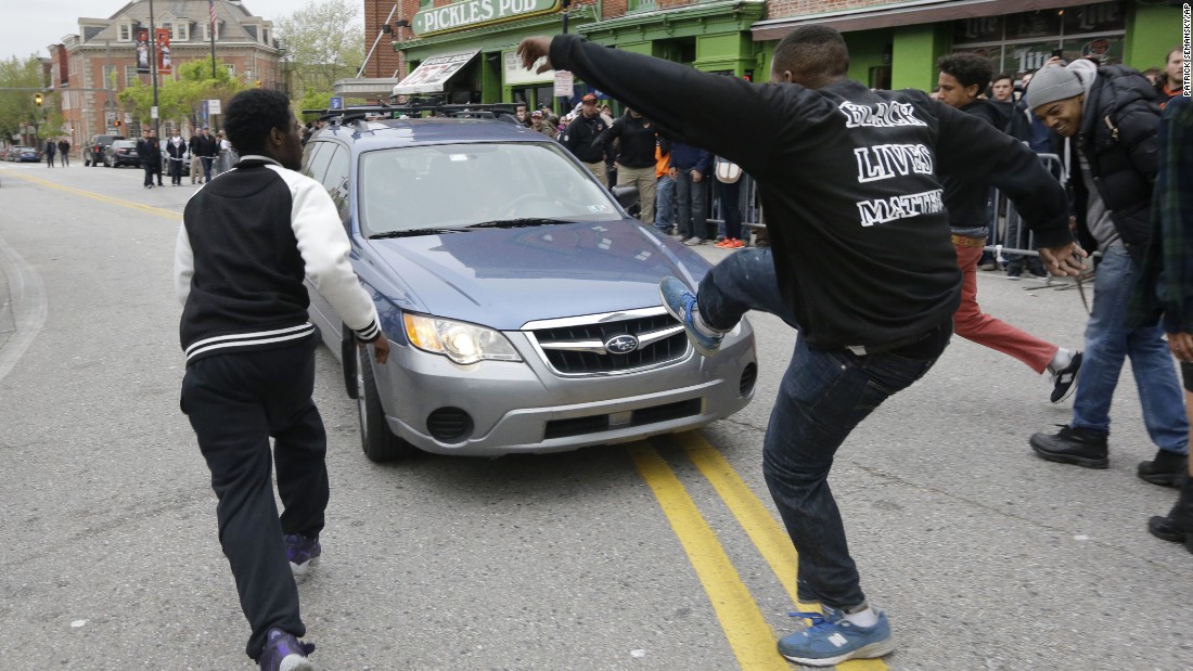 Protesters chase after a car as it drives in reverse after the rally on April 25.