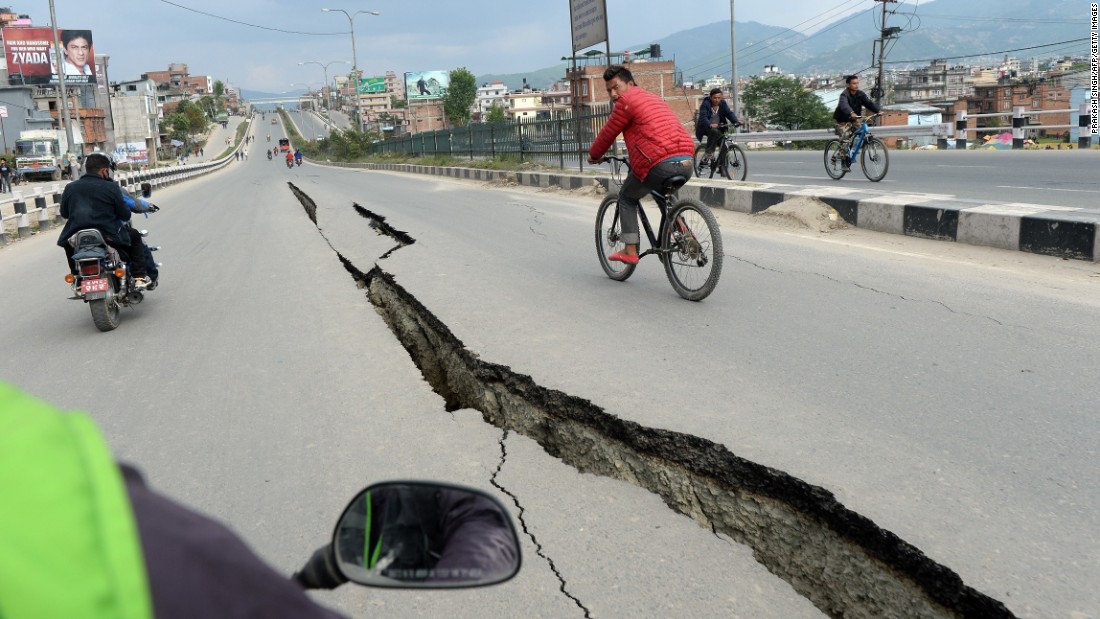 Residents cycle over damaged roads on the outskirts of Kathmandu on Sunday, April 26.