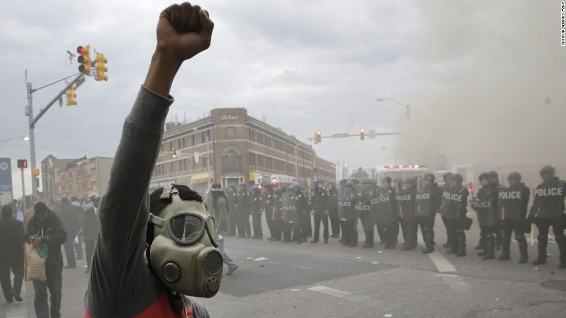 A demonstrator raises his fist as police stand in formation on April 27.