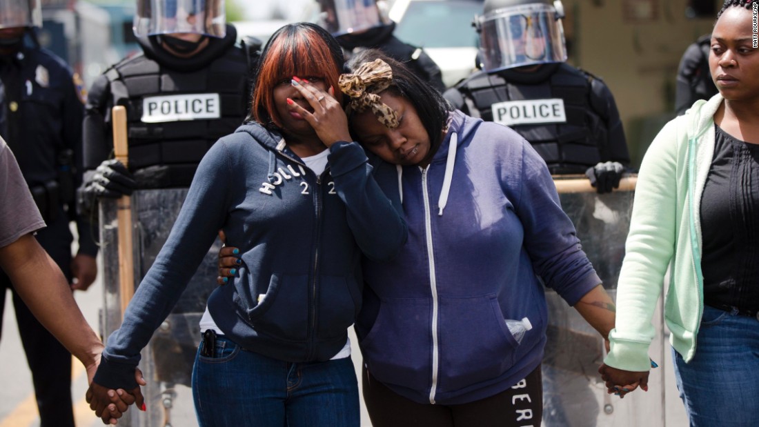 Jerrie Mckenny, left, and her sister Tia Sexton embrace as demonstrators hold hands and sing the hymn &quot;Amazing Grace&quot; in Baltimore on April 28. 