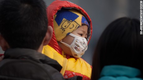 An infant wearing a mask was carried along a street in severe pollution in Beijing on January 12, 2013.
