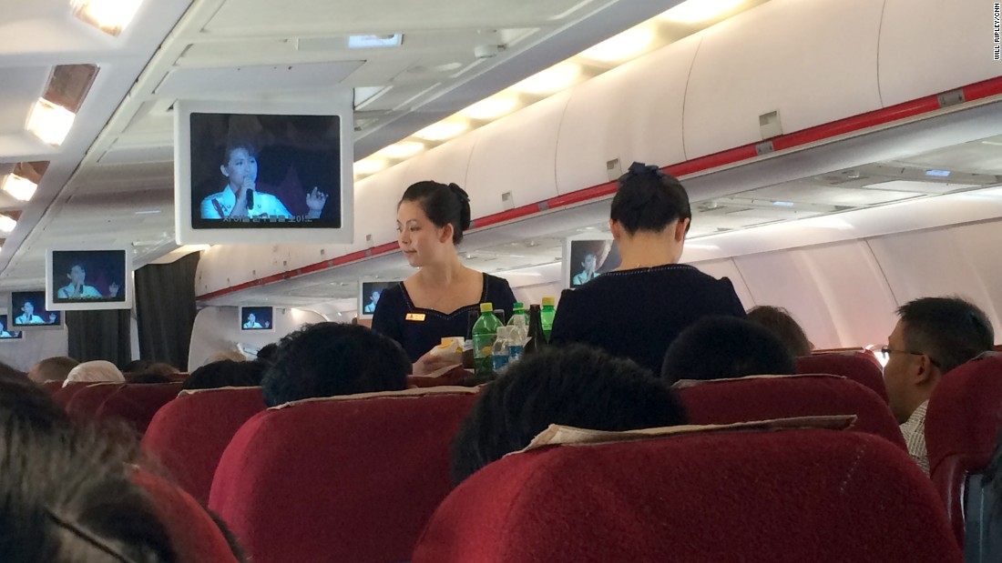 The flight attendants on Air Koryo serve refreshments as monitors show a North Korean televised concert mainly featuring patriotic songs about the military.