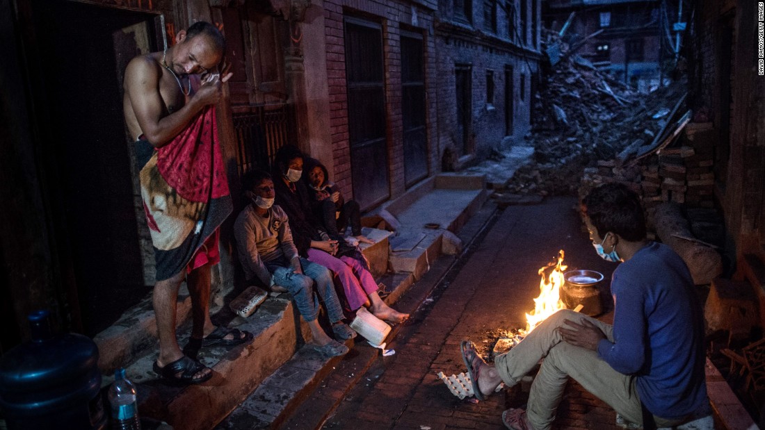 Members of the Tsayana family warm themselves next to a fire outside their damaged house on May 3 in Bhaktapur, Nepal.