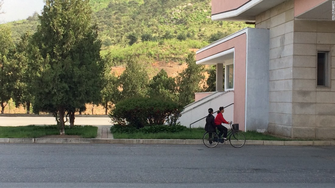 Two women share a bicycle as they head south on a highway leading from Pyongyang to the DMZ.