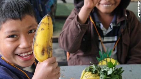 Students show off their &quot;purchases&quot; at a pretend market in school. The exercise encourages them to choose local fruits and vegetables over junk food.  