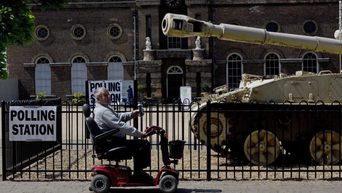 A man rides a mobility scooter past a an armored vehicle outside the polling station at the Greenwich Heritage Centre in London.