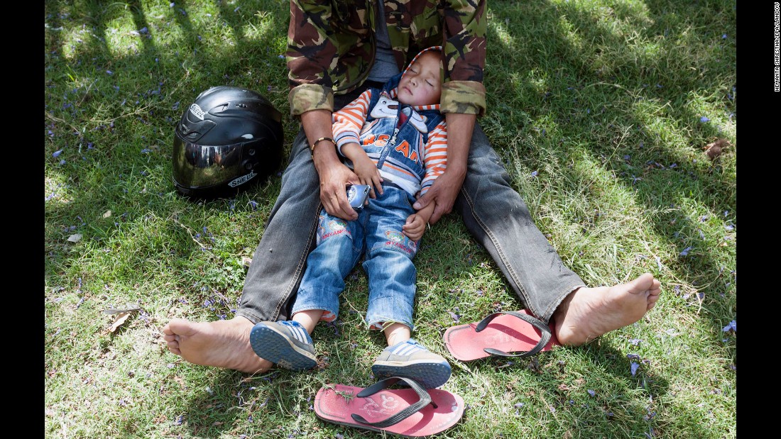 A boy sleeps in his father&#39;s lap after they moved to an open area in the Tundikhel area of Kathmandu on May 12.