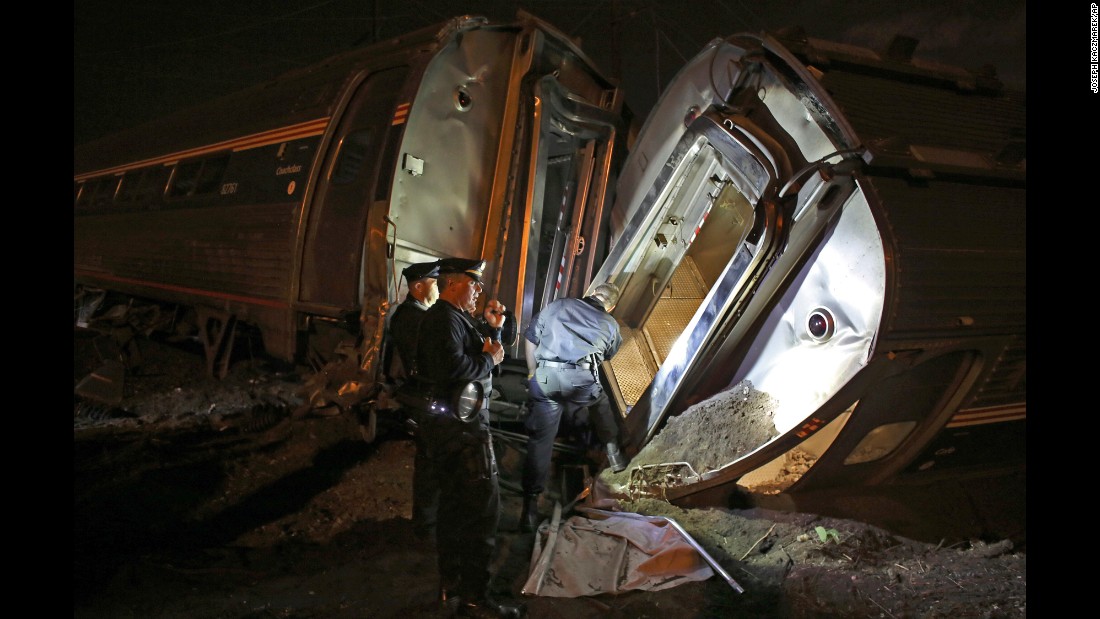 Police stand between two overturned train cars on Tuesday, May 12.