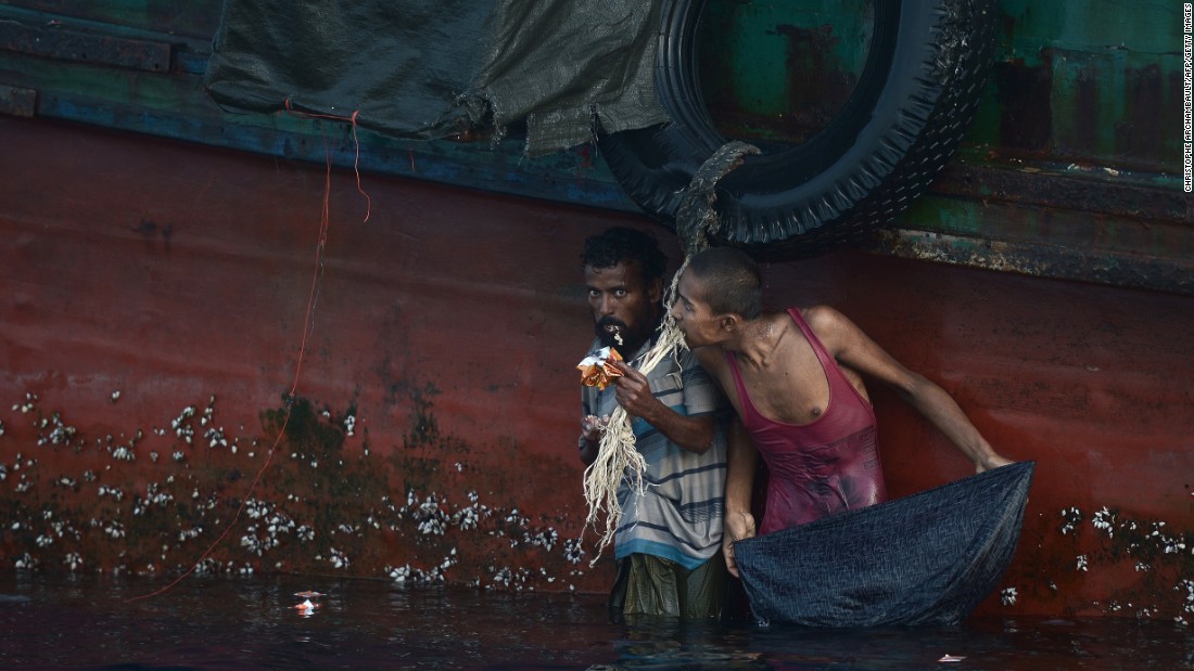 A Rohingya migrant eats food dropped by a Thai army helicopter after he swam to collect the supplies at sea. Malaysia, meanwhile, is processing more than 1,000 recently arrived migrants.