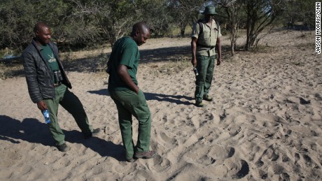 Trackers search for rhino prints near a watering hole. 