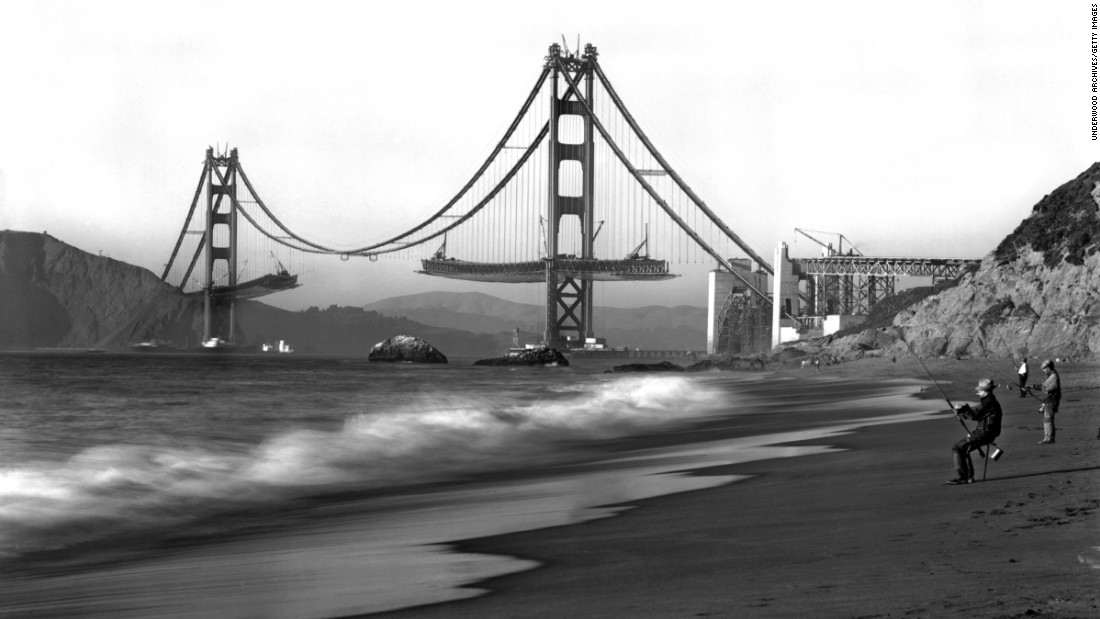 Fishermen on Baker Beach enjoy the view of the Golden Gate Bridge under construction. Work on the bridge began on January 5, 1933, and lasted four years and four months. The span is painted a distinctive color named &quot;international orange.&quot;