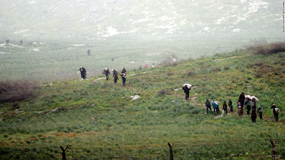 Syrian refugees walk across a field in Syria before crossing into Turkey on March 14, 2012.