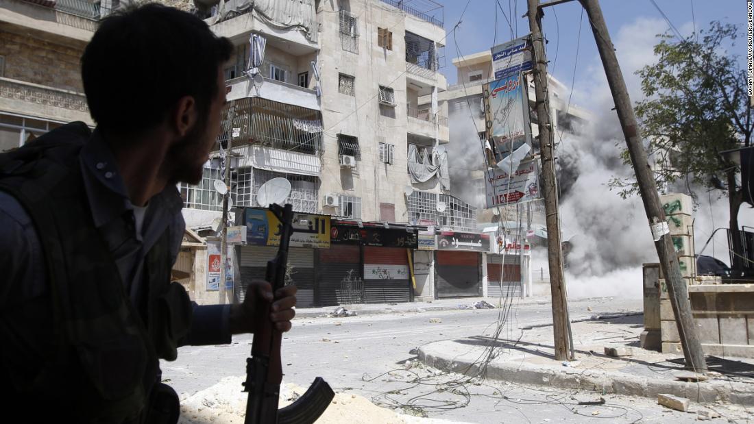 A Free Syrian Army fighter runs for cover as a Syrian Army tank shell hits a building across the street during clashes in the Salaheddine neighborhood of central Aleppo on August 17, 2012.