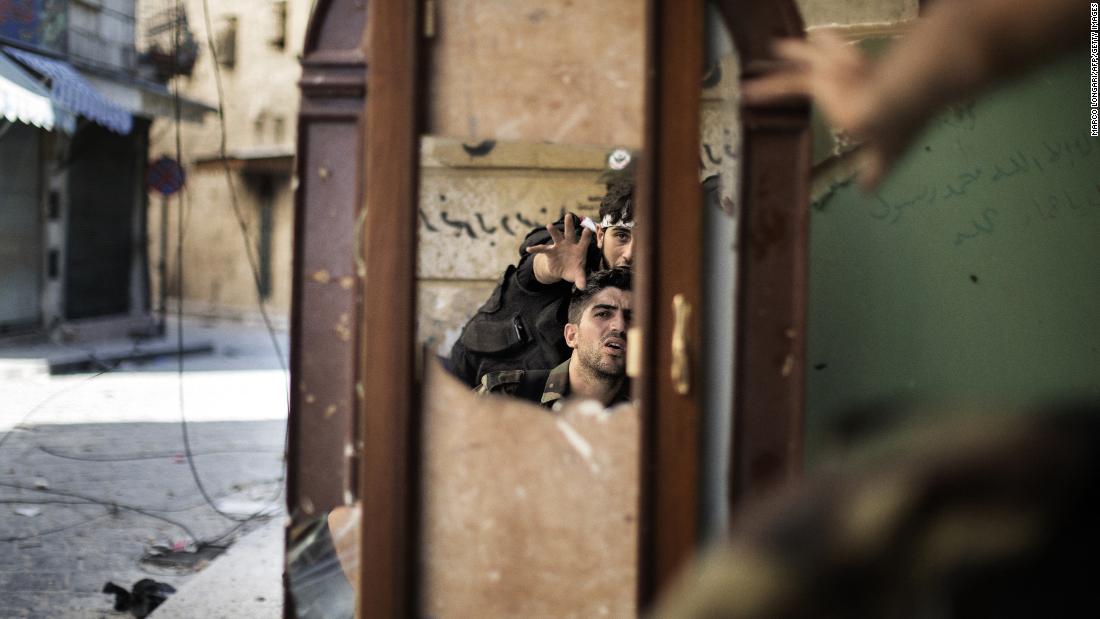 Free Syrian Army fighters are reflected in a mirror they use to see a Syrian Army post only 50 meters away in Aleppo on September 16, 2012.