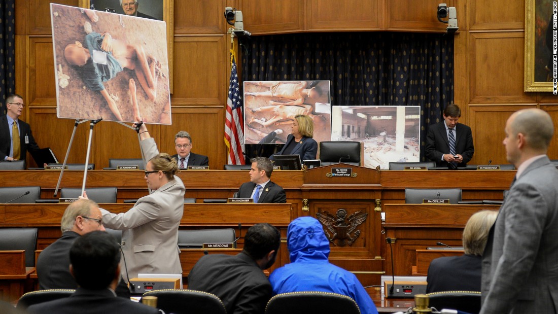 Photographs of victims of the Assad regime are displayed as a Syrian army defector known as &quot;Caesar,&quot; center, appears in disguise to speak before the House Foreign Affairs Committee in Washington. The July 31, 2014, briefing was called &quot;Assad&#39;s Killing Machine Exposed: Implications for U.S. Policy.&quot; Caesar, apparently a witness to the regime&#39;s brutality, smuggled more than 50,000 photographs depicting the torture and execution of more than 10,000 dissidents. CNN cannot independently confirm the authenticity of the photos, documents and testimony referenced in the report.