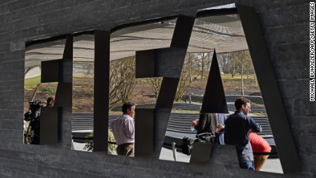 Caption:Member of the media wait next to a logo of the Worlds football governing body, at the FIFA headquarters in Zurich, prior to a press conference of FIFA President Sepp Blatter on March 20, 2015, closing a two-day meeting to decide the dates of the 2022 World Cup in Qatar. AFP PHOTO / MICHAEL BUHOLZER (Photo credit should read MICHAEL BUHOLZER/AFP/Getty Images)
