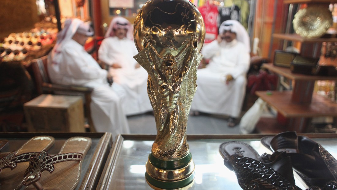 Men at a shoemaker&#39;s stall sit by a replica of the World Cup trophy soon after the hosting award brought announcements of a wide variety of infrastructure projects, including the construction of new stadiums and roads.