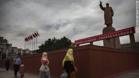  A veiled Muslim Uyghur woman walks passed a statue of Mao Zedong on July 31, 2014 in Kashgar, Xinjiang.