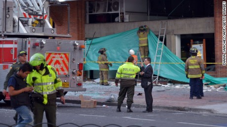 Colombian police officers and firefighters check the site of an explosion in the financial heart of Bogota.