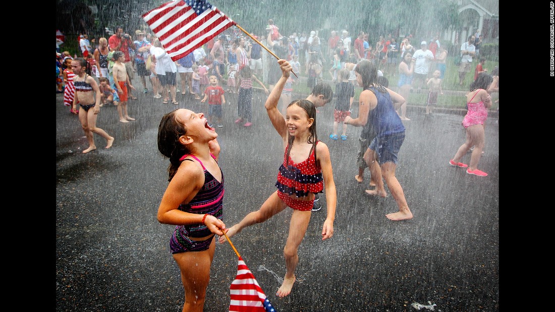 Cousins Ann Claire Schenkel, left, and Greer Shenkel dance around Aurora Circle in the spray of a fire hose after a July Fourth parade in Memphis, Tennessee, on Saturday.