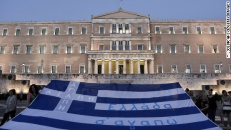 Demonstrators display the Greek flag in front of parliament on July 15, 2015 in Athens, Greece. Anti-austerity protesters hurled petrol bombs at police in front of Greece's parliament as lawmakers began debating deeply unpopular reforms needed to unlock a new eurozone bailout. Riot police responded with tear gas against dozens of hooded protesters who set ablaze parts of Syntagma square in central Athens
