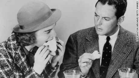 A man expresses disapproval at his friend&#39;s table manners as she sinks her teeth greedily into a sandwich, circa 1940. 