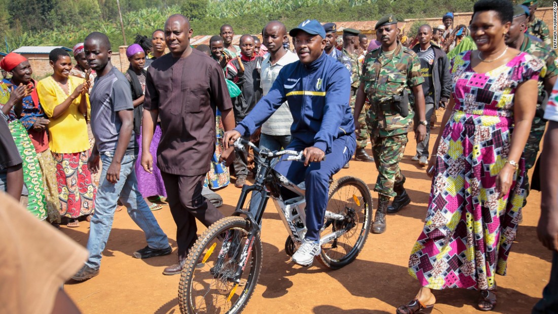 Nkurunziza is accompanied by first lady Denise Bucumi Nkurunziza, right, as he arrives on a bicycle to cast his vote in Ngozi, Burundi, on Tuesday, July 21.