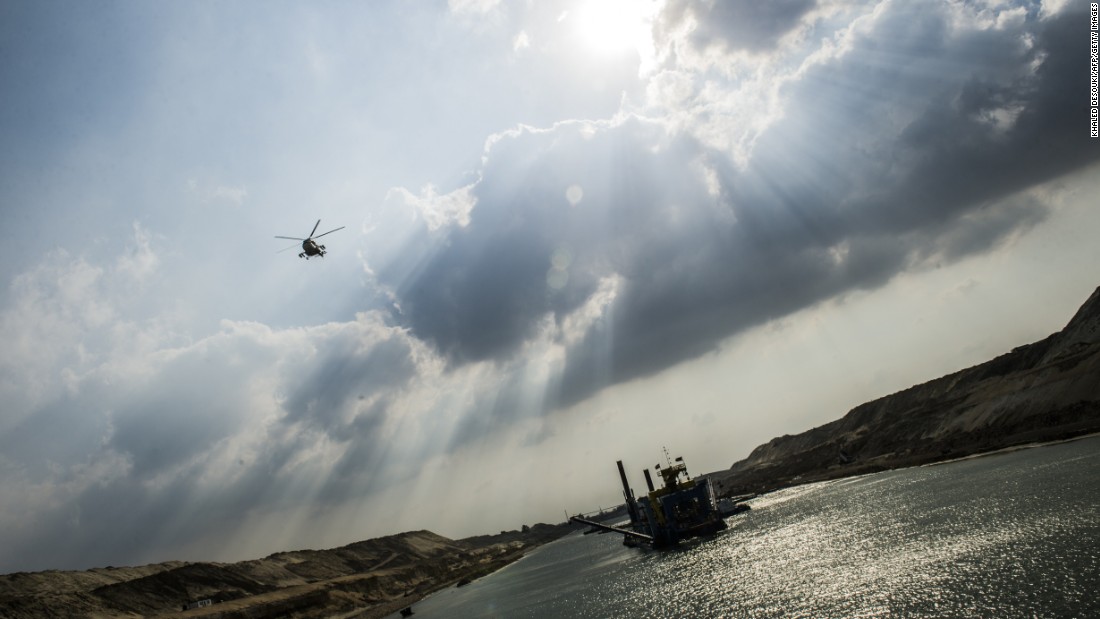 An Egyptian army helicopter flies over a dredger at work on the new waterway of the Suez Canal on June 13, 2015, in the port city of Ismailia, east of Cairo. The government hopes the ambitious industrial project will generate $100 billion in revenue and create 1 million jobs.