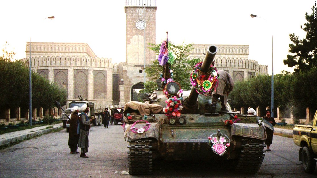 Tanks manned by Taliban fighters are decorated with flowers in front of the presidential palace in Kabul on September 27, 1996.