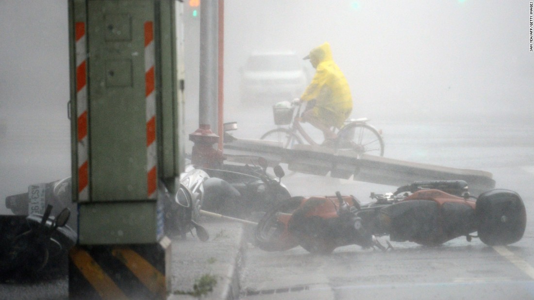 A man rides past blown-down motorcycles as Typhoon Soudelor hits Taipei on August 8.