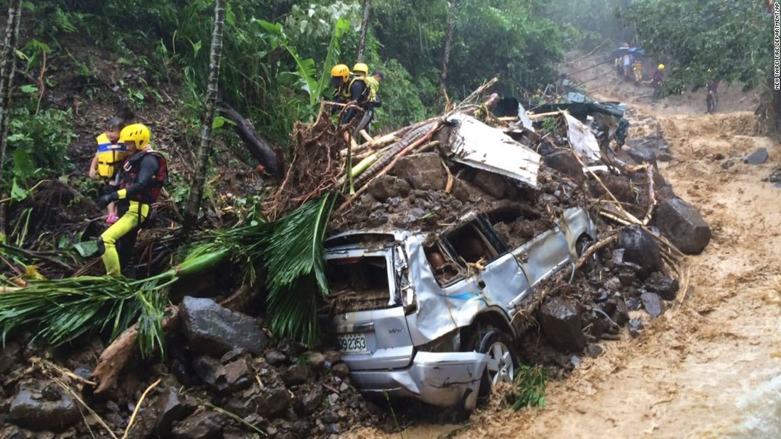 Emergency rescue personnel carry children past cars crushed by a mudslide in New Taipei City on August 8. 