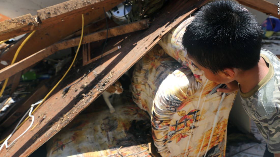 A young boy finds a mother cat nursing two kittens as he searches through the storm-damaged remains of his home on August 8 in Saipan, Northern Mariana Islands. 