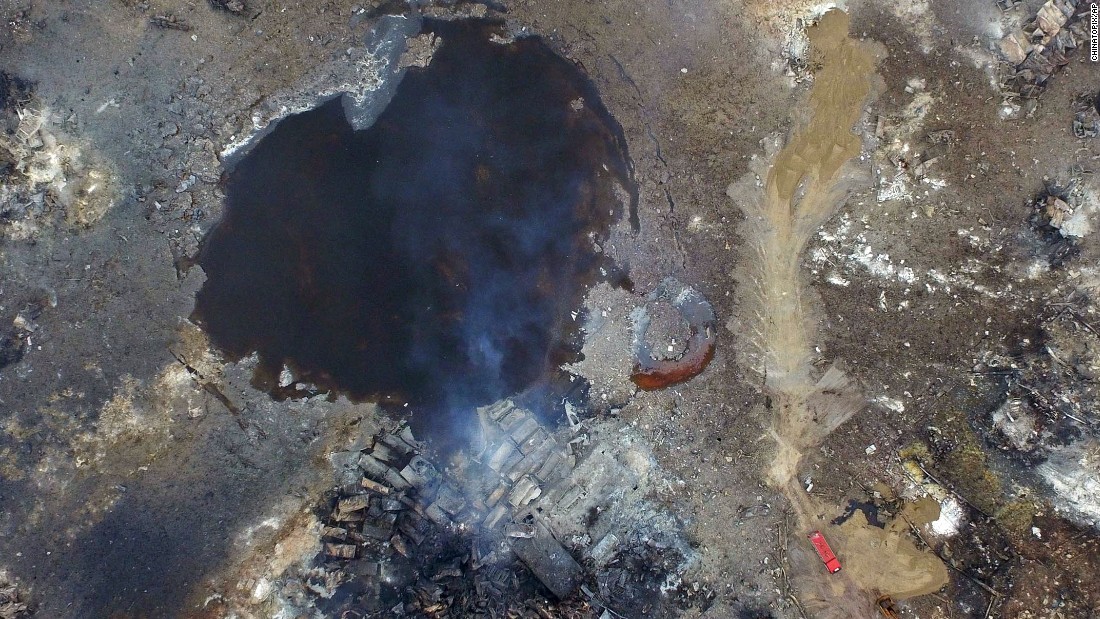 Smoke rises from debris on Saturday, August 15, near a crater that was at the center of a series of explosions in northeastern China&#39;s Tianjin municipality as seen from an aerial view.