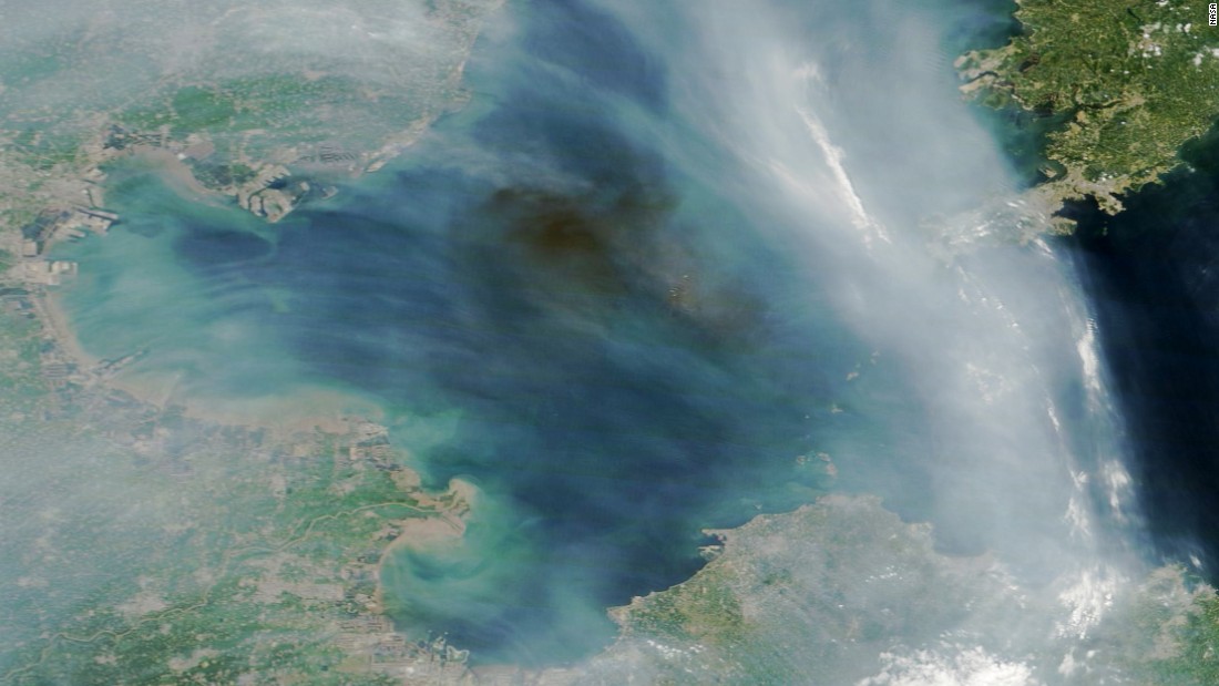 A dark plume of smoke drifts over the Bohai Sea off the east coast of China. The source of the smoke appears to be industrial fires caused by explosions at a port in Tianjin, China. The streams of light gray smoke in the image likely were caused by wildfires in eastern China. NASA&#39;s Terra satellite captured the images at 2:30 Universal Time (10:30 a.m. local time) on August 13, 2015.