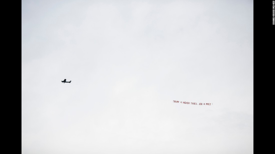 A pro-Jeb Bush plane flies by the stadium with banner &quot;Trump 4 higher taxes. Jeb 4 Prez.&quot; Bush&#39;s official campaign said it emailed supporters in Alabama pointing out Trump&#39;s previous liberal positions on abortion, gun rights and tax issues.