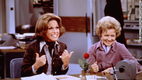 American actress Mary Tyler Moore (as Mary Richards) (left) gives a &#39;thumbs up&#39; sign as she sits at her desk with Betty White (as Sue Ann Nivens) in a scene from &#39;The Mary Tyler Moore Show&#39; in 1975.