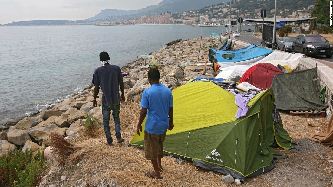 Migrants walk on a rocky beach in Ventimiglia, Italy, where they set up camp near the French border.