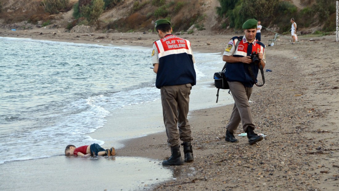 Authorities stand near Alan&#39;s lifeless body on September 2, 2015. This photo went viral around the world, often with a Turkish hashtag that means &quot;Flotsam of Humanity.&quot;