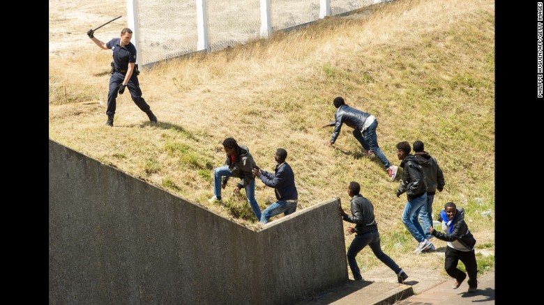 A police officer in Calais, France, tries to prevent migrants from heading for the Channel Tunnel to England in June 2015.