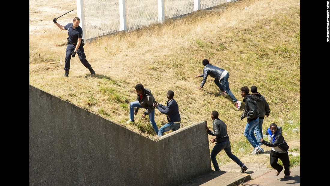A police officer in Calais, France, tries to prevent migrants from heading for the Channel Tunnel to England in June 2015.