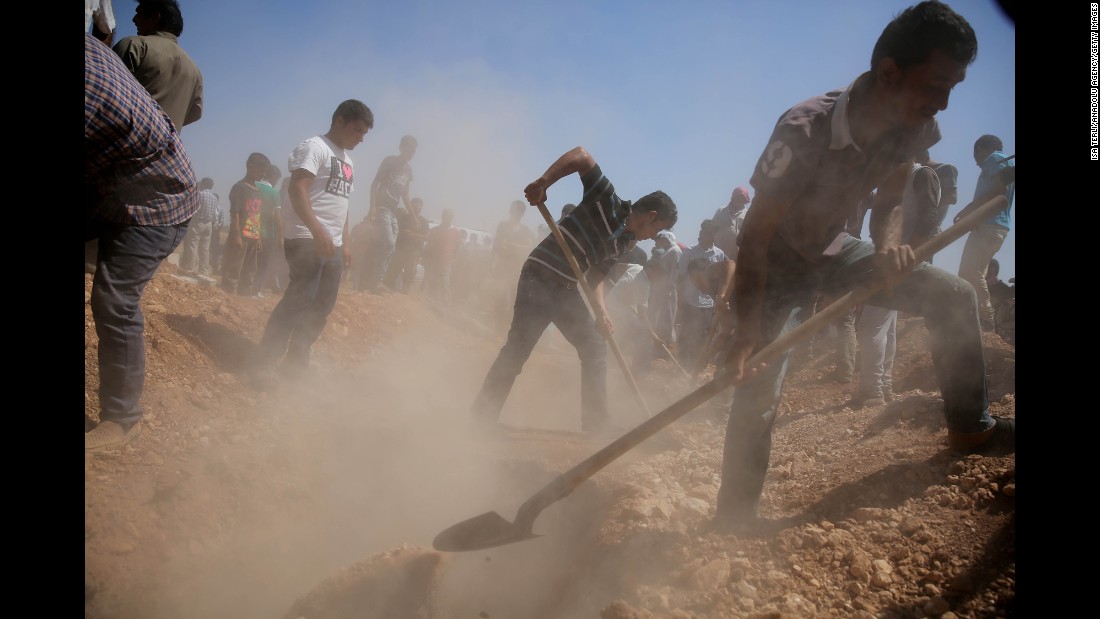 Men dig graves for the three coffins in Kobani on September 4, 2015.
