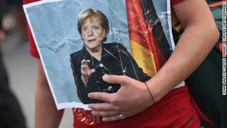 A Syrian refugee holds a picture of German Chancellor Angela Merkel as he and hundreds of others arrive in Munich.